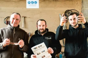 Mickaël Lescouët, Jean-Yves Pernes et Gabin Grosmaitre dans l’atelier : une signalétique au mur recommande le port des équipements de protection, lunettes et casque anti-bruit sont à disposition de l’opérateur.