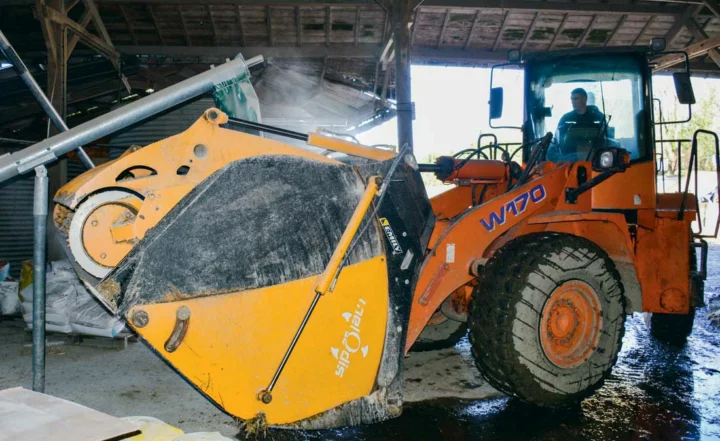 Lorsque l’ensilage est chargé dans le godet l’éleveur se positionne sous la goulotte pour incorporer le mélange d’aliments secs.