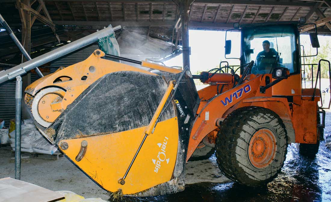 Lorsque l’ensilage est chargé dans le godet l’éleveur se positionne sous la goulotte pour incorporer le mélange d’aliments secs. - Illustration Un godet connecté pour l’alimentation des laitières