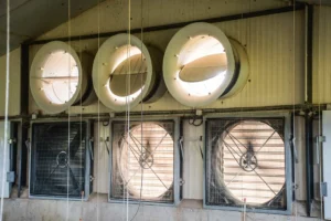 Sur le pignon, en fond de bâtiment, le système assurant le fonctionnement de la ventilation longitudinale : 3 ventilateurs (dont un progressif au centre) et 7 turbines en bas.