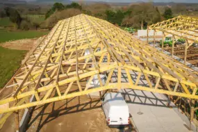 Vue d’ensemble d’une charpente en double chapelle en treillis en construction à Loguivy-Plougras.