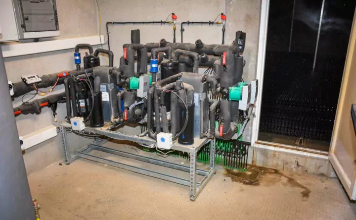 Le local technique. Derrière la porte, les calories sont récupérées sous le laveur d'air par un gaz contenu dans les tuyaux verts. Ces tuyaux présentent des caractéristiques uniques de résistance à l'ammoniac, selon le concepteur.