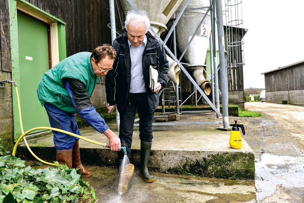 Patrick Robert, éleveur laitier à Bréhand-Moncontour montre à Félix Mahé comment, en les déchaussant à moitié, il est facile de nettoyer le dessous des bottes avant d’entrer dans la stabulation. Qui dit « bio sécurité » n’exclut pas bon sens paysan et pragmatisme ! - Illustration Le GDS Bretagne prend les devants