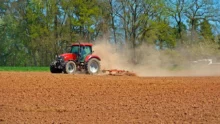 Tracteur qui travaille dans un champ sec et poussiéreux.