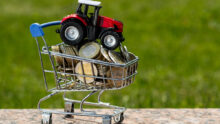 TRACTEUR MINIATURE DANS UN CADDIE REMPLI DE PIÈCES DE MONNAIE