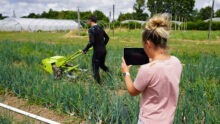 Une femme et un homme dans un champ en train de mesurer des points de tension grâce à une combinaison connectée