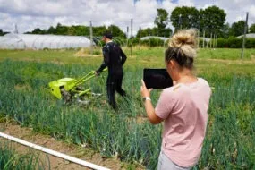 Une femme et un homme dans un champ en train de mesurer des points de tension grâce à une combinaison connectée