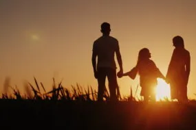 Une famille qui se tient la main devant un coucher de soleil