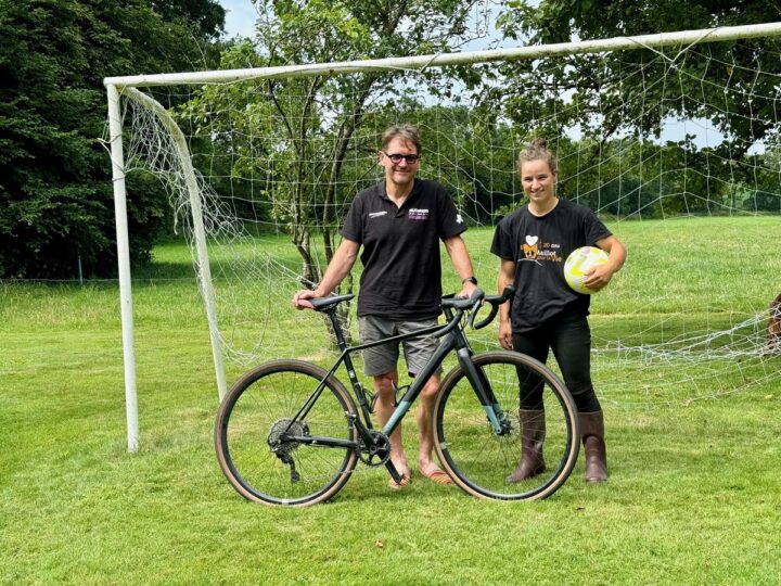 Un éleveur avec son vélo accompagné par sa salariée tenant un ballon de football.