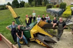 Des agriculteurs et leurs enfants autour d'une ensileuse ancienne deux rangs.