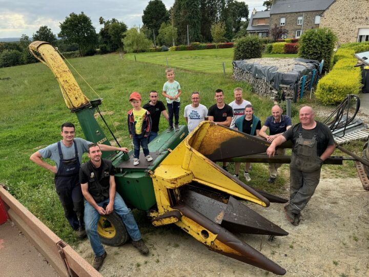 Des agriculteurs et leurs enfants autour d'une ensileuse ancienne deux rangs.