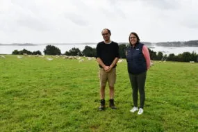 Michel Le Derf et Morgane Talidec avec les moutons et la mer dans le fond