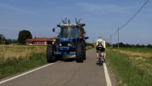 un tracteur et des vélos se croisent sur une route de campagne