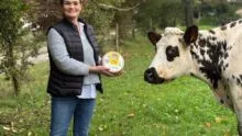 Estelle Viel dans un champ avec un fromage au lait cru et une vache