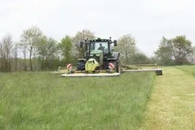 Un tracteur réalise un chantier de fauche de l'herbe.