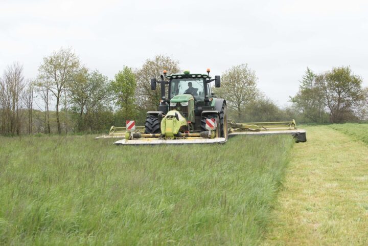 Un tracteur réalise un chantier de fauche de l'herbe.
