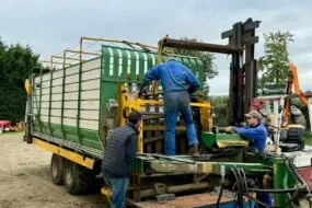 Deux mécaniciens agricoles et un éleveur autour d'une remorque en réparation