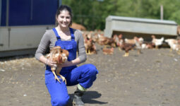 Une jeune femme souriante avec un poulet dans les mains
