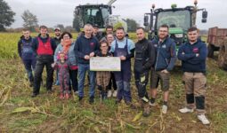 Un groupe de jeunes agriculteurs devant une ensileuse et un tracteur