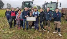 Un groupe de jeunes agriculteurs devant une ensileuse et un tracteur