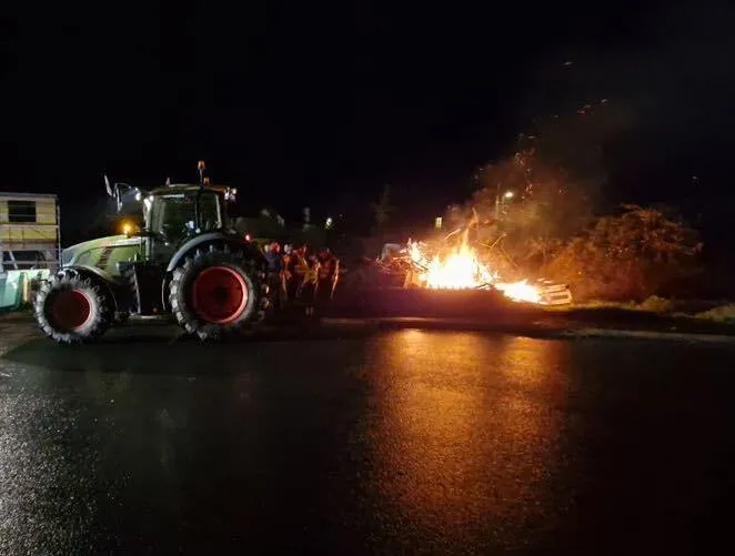 Feu de colère dans la nuit avec un tracteur à côté - Illustration La colère repart
