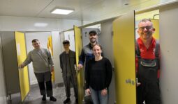 Quatre hommes et une femme présentent les nouveaux vestaires d'un élevage de porc.