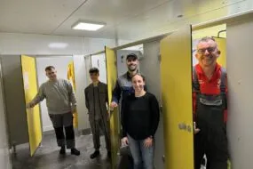 Quatre hommes et une femme présentent les nouveaux vestaires d'un élevage de porc.