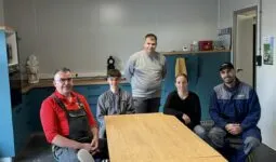 Quatre hommes et une femme travaillant dans une salle de pause.