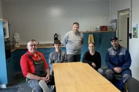 Quatre hommes et une femme travaillant dans une salle de pause.