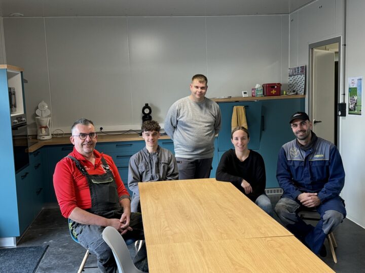 Quatre hommes et une femme travaillant dans une salle de pause.