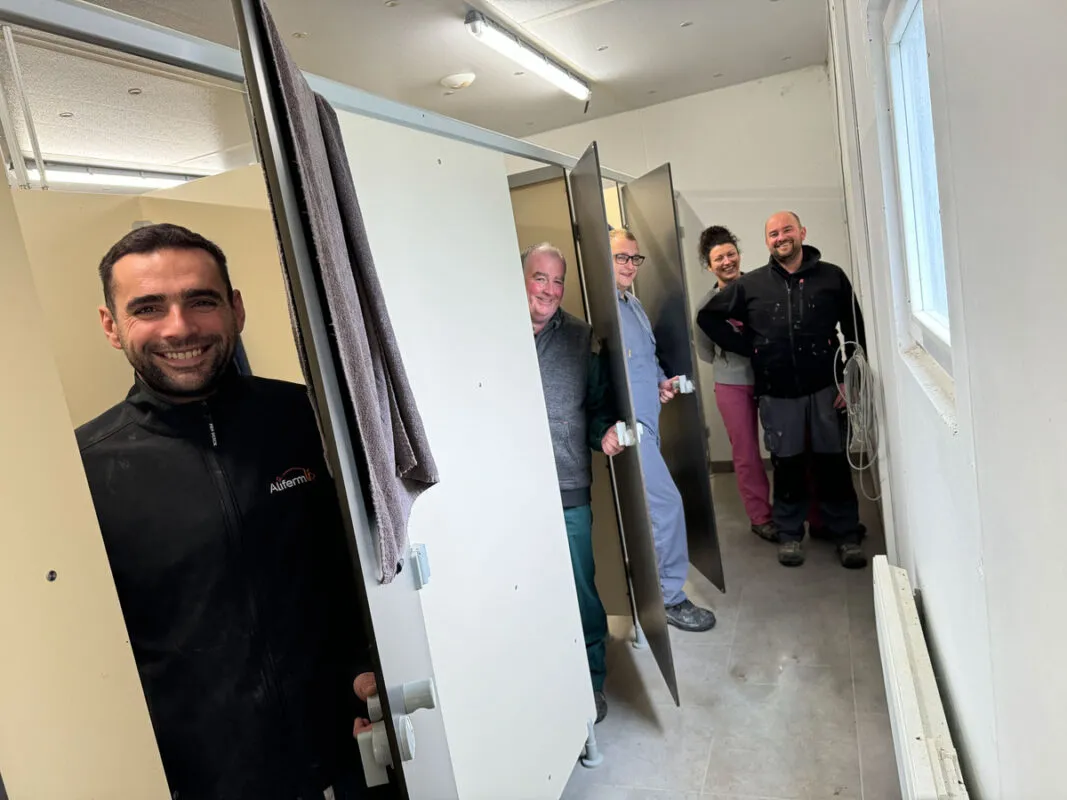 Quatre hommes et une femme dans les vestiaires d'un élevage porcin.