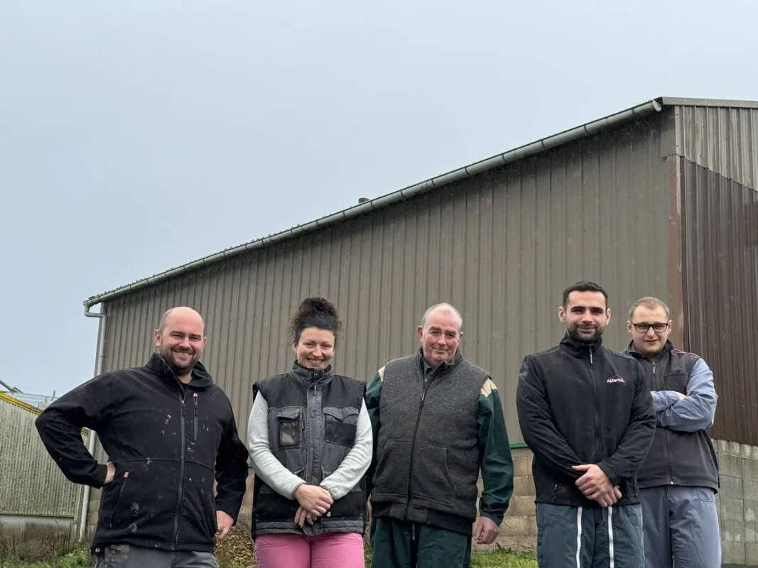 Quatre hommes et une femme devant un bâtiment en élevage porcin.