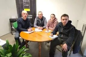 Les deux éleveurs et leurs deux salariés dans le bureau assis autour d'une table.