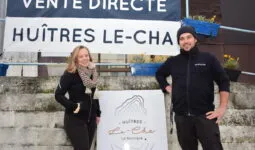 Un couple devant la banderole de vente directe des huîtres Le-Cha