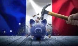 Une tirelire qui se casse sous le poids d'un marteau avec en fond le drapeau français