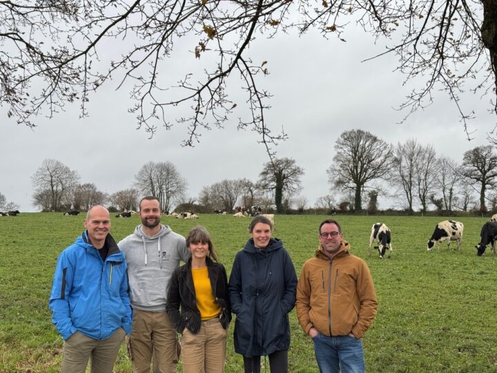 Trois hommes et deux femmes devant un eprairie avec des vaches laitières au pâturage