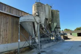 Des silos d'aliments à côté d'un bâtiment d'élevage laitier