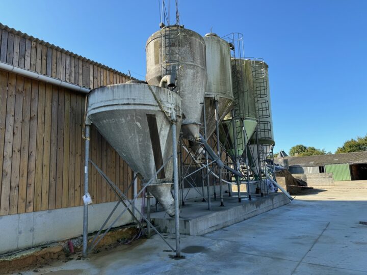 Des silos d'aliments à côté d'un bâtiment d'élevage laitier
