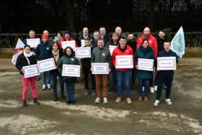 Les membres de la liste portent des panneaux et drapeaux devant une stabulation