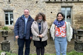 deux femmes et un hommes devant une maison
