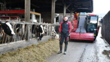 Alexis Robert devant la mélangeuse dans le couloir d'alimentation avec les vaches