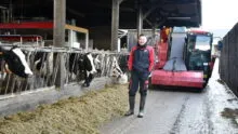 Alexis Robert devant la mélangeuse dans le couloir d'alimentation avec les vaches