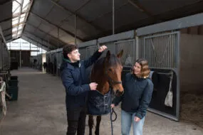 Un étudiant et une étudiante avec un cheval.