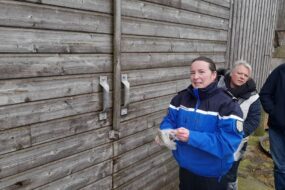 Un gendarme et 2 personnes devant la porte d'un bâtiment agricole
