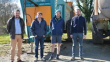 Quatre hommes devant du matériel agricole