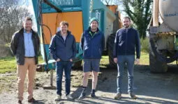 Quatre hommes devant du matériel agricole