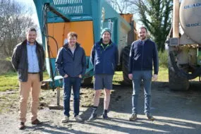 Quatre hommes devant du matériel agricole