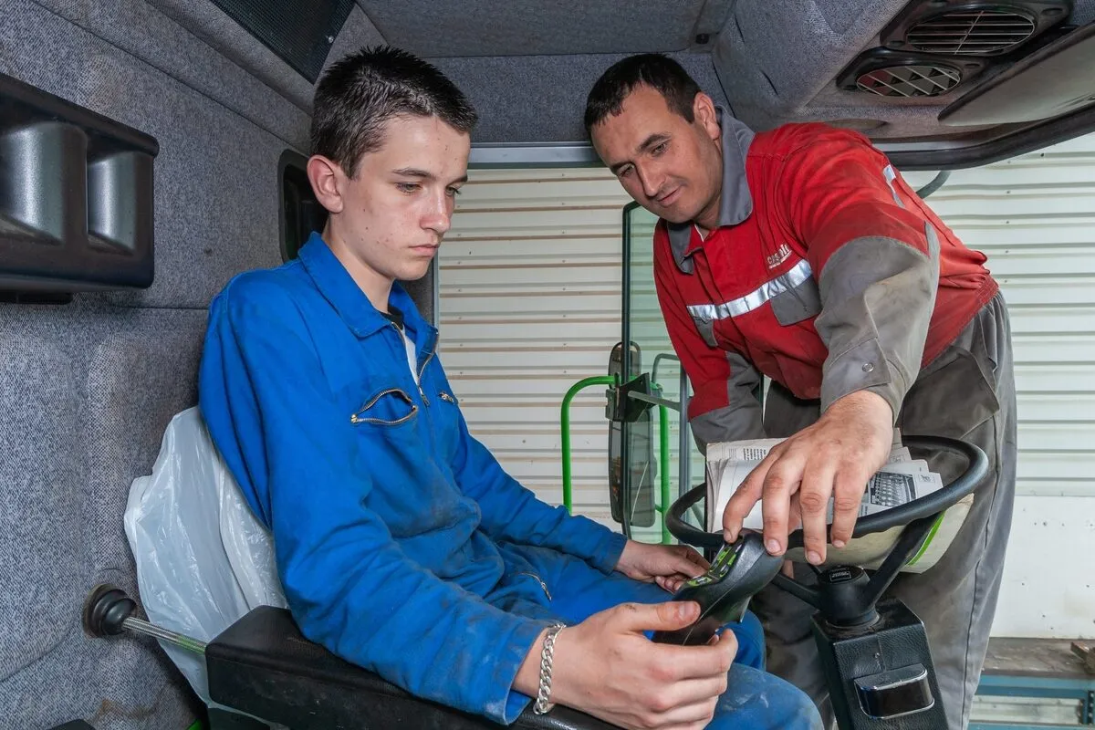 Un agriculteur en train de former un jeune dans une cabine de tracteur - Illustration Prévention des accidents  du travail : un enjeu majeur
