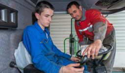Un agriculteur en train de former un jeune dans une cabine de tracteur
