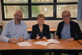Trois personnes signent un partenariat